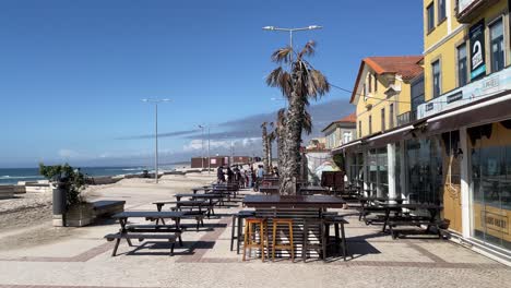 People-outside-cafe-oceanside-Furadouro-beach,-sunny-Spring-day