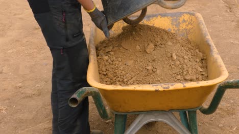 Transporting-dirt-and-sand-into-an-old-wheelbarrow