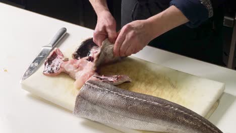 Chef-cleaning-hake's-head-over-a-kitchen-counter-at-Spanish-restaurant