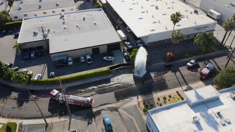 Aerial-view-of-firetruck-calming-a-Fire-Hydrant-Burst,-in-Los-Angeles--orbit,-drone-shot
