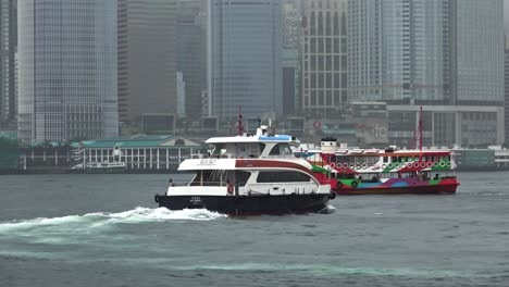 Eine-Stationäre-Aufnahme-Eines-Kreuzenden-Schiffs-Und-Der-Star-Ferry,-Die-Durch-Die-Gewässer-Des-Victoria-Harbour-In-Hongkong-Fährt
