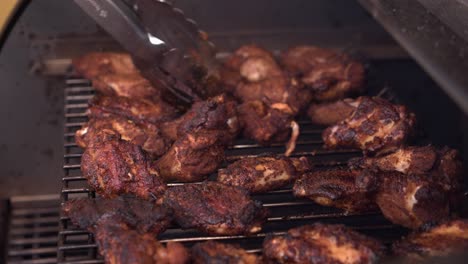 Chicken-wings-and-drumsticks-on-hot-BBQ-grill-are-turned-with-tongs