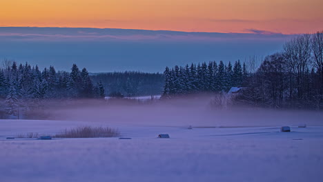 Shot-of-snowy-fields-with-round-hay-bales-on-a-cold-Winter-evening-with-fog-passing-by-in-timelapse