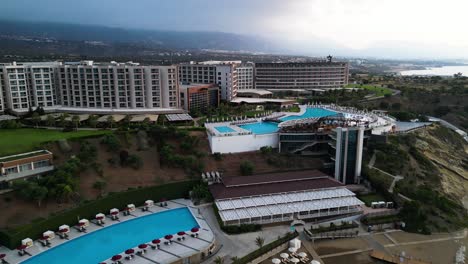 Nicosia,-Cyprus-:-Aerial-drone-forward-moving-shot-over-Elexus-Hotel-with-a-empty-big-pool-on-a-cloudy-day