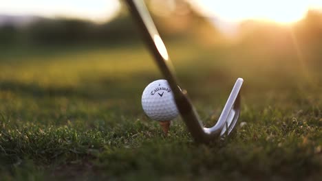 Golfschläger-Und-Callaway-Golfball-Im-Gras-Mit-Sonnenuntergangshintergrund---Nahaufnahme