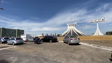 Driving-by-the-Metropolitan-Cathedral-of-Brasília-along-the-Ministries-Esplanade-in-Brasilia,-Brazil