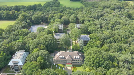 Aerial-of-inspirational-office-buildings-with-solar-panels-on-rooftop-surrounded-by-green-forest-in-summer