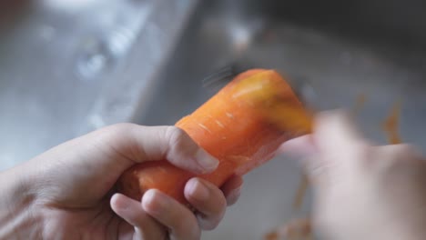 Hand-Mit-Schäler,-Um-Frische-Karottenschale-Zu-Schälen,-Die-Zum-Kochen-Vorbereitet-Wird