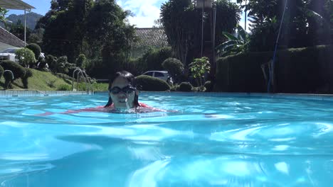 Chica-Con-Gafas-De-Natación-Disfrutando-Nadando-En-La-Piscina-Al-Estilo-Rana