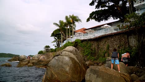 Menschen,-Die-Durch-Große-Steine-An-Der-Felsigen-Küste-In-Der-Nähe-Des-Strandresorts-Bombas-Und-Bombinhas,-Brasilien,-Spazieren