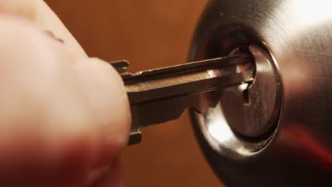 Macro-shot-of-a-silver-key-inserted-into-lock-of-an-internal-doorknob-lock