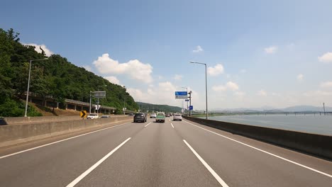 Verkehr-In-Seoul-–-Fahrerperspektive-Auf-Der-Mehrspurigen-Schnellstraße-Gangbyeonbuk-ro-In-Der-Nähe-Des-Han-Flusses-Am-Koreanischen-Nationalfeiertag,-Als-Flaggen-An-Lichtmasten-Angebracht-Werden,-Tagsüber-Bewölkt-Und-Sonnig