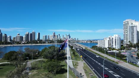 Australian-flag-waving-in-a-strong-breeze-next-to-a-busy-road-network-leading-into-a-towering-city-skyline
