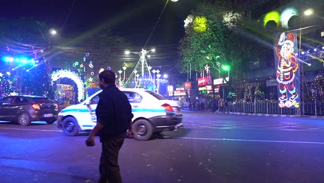 Beautifully-decorated-Park-street,-Kolkata,-India-on-Christmas-eve-with-people-and-traffic-passing-by-watching-the-fully-decorated-streets-with-lights