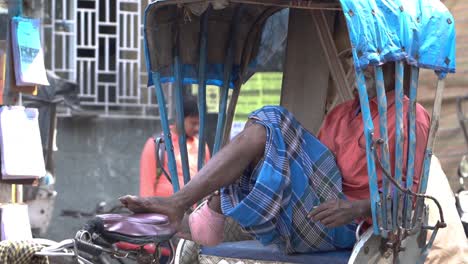 Poor-and-tired-old-man-relaxing-in-his-rickshaw,-Indian-rickshaw-driver