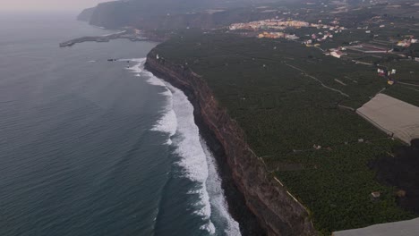 Aerial-forward-along-cliffs-with-banana-plantation-fields-invaded-by-solidified-lava,-La-Palma-island