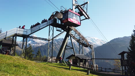 Gondola-on-the-hanger-with-people-and-mountain-alps-in-the-background