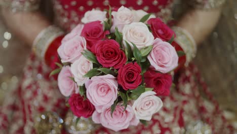 Indian-bride-holding-bouquet-of-red-and-pink-roses-in-hand-on-wedding-day