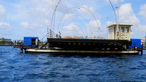The-Queen-Emma-Bridge,-a-pontoon-bridge-in-Willemstad,-Curacao,-swinging-closed-over-Saint-Anna-Bay-in-the-Caribbean