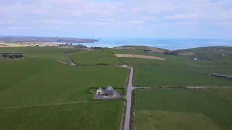 An-aerial-footage-over-country-road-and-green-fields-of-coastal-area-near-Kinsale,-Ireland