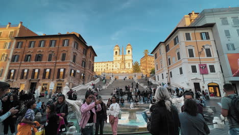 Dolly-forward-shot-showing-many-tourist-taking-pictures-in-front-of-lighting-church-Trinità-dei-Monti-and-Spanish-Steps