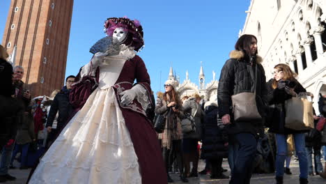 Masked-woman-poses-in-Venice-Carnival,-tourists-and-Italian-architecture-famous-buildings