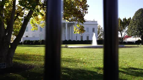 USA-White-House-building-behind-fence-with-majestic-fountain-on-sunny-day,-slide-right