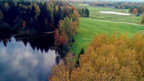 Szenische-Luftaufnahme-über-Einer-Rechteckigen-Hütte-Neben-Einem-Unberührten-See,-Umgeben-Von-Herbstlichen-Bäumen-In-Ländlicher-Umgebung-Bei-Tag