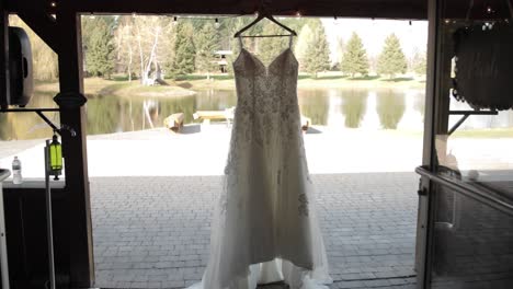 Verlassen-Eines-Rustikalen-Hochzeitsortes-Mit-Einem-Eleganten-Hochzeitskleid,-Das-Direkt-Vor-Dem-Eingang-Hängt,-Mit-Einem-Teich-Und-Bäumen-Im-Hintergrund-Auf-Der-Bean-Town-Ranch-In-Der-Nähe-Von-Ottawa,-Kanada