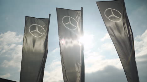 Black-banners-with-Mercedes-Benz-logo-blown-by-wind-against-sunlight