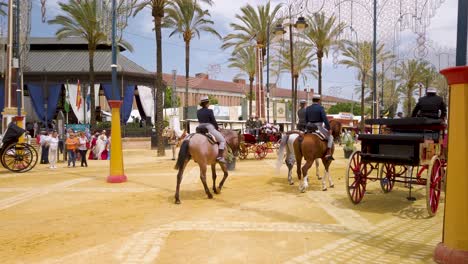 Three-people-ride-horses-through-fairgrounds-at-Jerez-Horse-Fair,-Spain