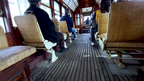 Wooden-old-tram-Interior-with-people-sitting-on-chairs-during-traveling-tour-in-Porto-city---back-view