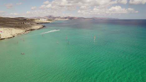 Stunning-aerial-drone-shot-of-water-sports-at-sunny-Playa-de-Sotavento-de-Jandía,-Fuerteventura,-beach,-spain