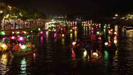 Colorful-Romantic-Dreamy-Atmosphere-at-Lantern-Festival-in-Hoi-An-Vietnam,-Panoramic-Night-View-of-illuminated-Boats-Canoes-Floating-Sailing-on-the-Canal-River,-Tourists-on-Board,-Tourism-Destination