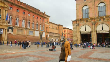 Shot-of-tourists-walking-around-Piazza-Maggiore-in-Emilia-Romagna,-historical-province-in-Bologna,-Italy-on-a-cloudy-day