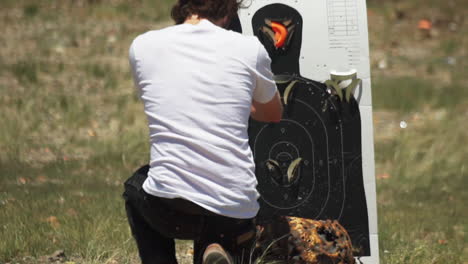 Caucasian-man-crouching,-inspects-and-resets-clay-target-holder-on-a-shooting-range