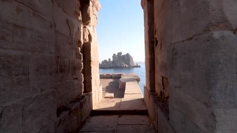 View-of-rocks-in-the-Nile-river-through-two-walls-of-Philae-temple-in-Aswan,-Egypt