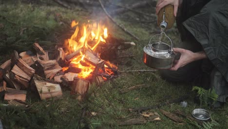 FIlling-a-kettle-with-water-next-to-a-bushcraft-bonfire-in-the-forest