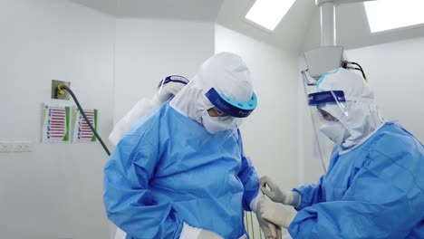 Asian-Nurse-and-Assistant-Help-Doctor-Put-On-PPE,-Isolation-Gown,-Personal-Protection-Equipment
