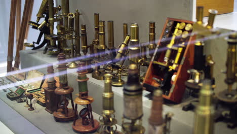 Rack-focus-to-a-group-of-ancient-brass-microscopes-displayed-in-an-optics-exhibition