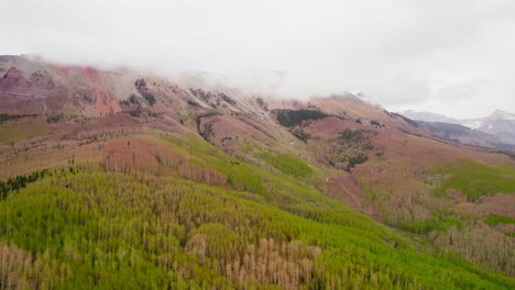 4K-Aerial-Drone-Footage-Of-Large-Mountain-Base-Covered-In-Aspen-Trees-With-Low-Clouds-Covering-Mountain-Peak-During-Cloudy-Rainy-Day