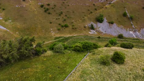 Aerial-view-above-rustic-stone-boundary-wall-on-idyllic-Peak-district-hiking-valley-countryside