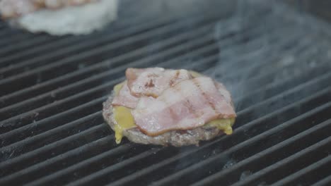 Chef-takes-burger-meat-with-cheese-and-bacon-off-the-smoking-grill