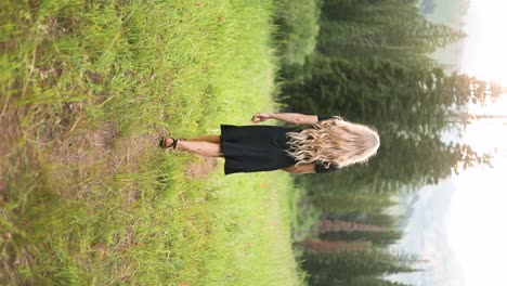 Beautiful-Blonde-Woman-Walking-Peacefully-in-Green-Forest,-Vertical