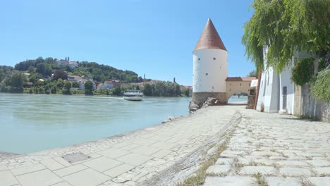 Cruise-ship-on-tour-on-Inn-River-by-Schaibling-Tower-in-Passau,-Germany
