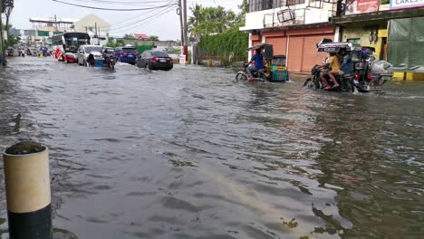 Flooded-highway,-after-tropical-storm-on-Dagupan-City,-commuters-car-and-public-vehicle-slowly-driving-through-submerged-roadway