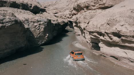Jeep-Renegade-Longitude-explore-narrow-canyon-gap,-driving-in-shallow-river