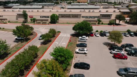 Round-Rock-Premium-Outlets-Aerial-Drone-pull-away-from-shops-in-parking-lot-on-sunny-summer-day-in-Texas-in-4k
