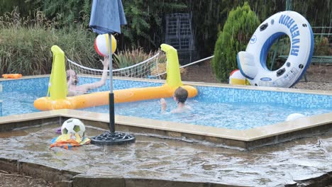 Vater-Und-Sohn-Spielen-Während-Eines-Regensturms-Fröhlich-Schwimmbadvolleyball