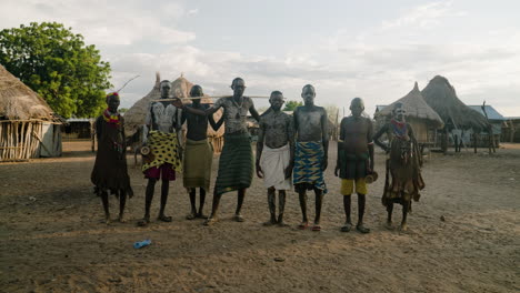 Ureinwohner-Des-Karo-Stammes-Mit-Körperbemalung-Stehen-Mit-Strohgedeckten-Häusern-Im-Hintergrund-Im-Omo-Tal,-Äthiopien